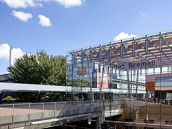 View of glass hall with boulevard and drop tower in the background